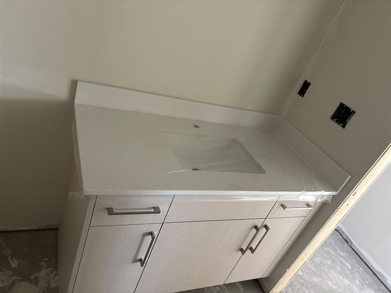Linen-textured flat-panel vanity with brushed nickel pulls and a white quartz top with backsplash