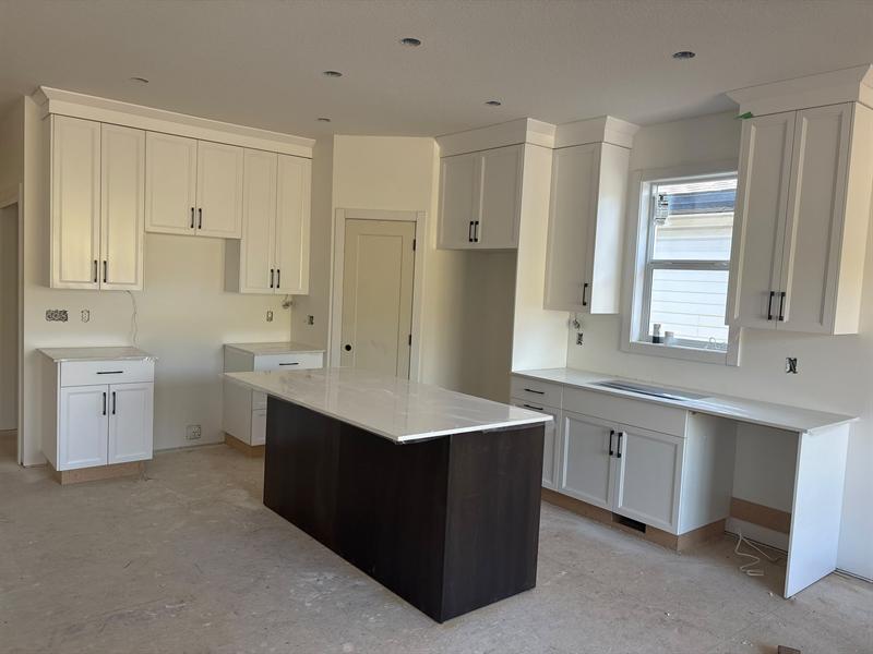 White shaker perimeter cabinets with crown moulding and a dark espresso island with a white top